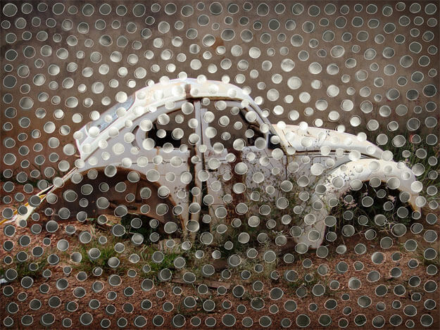 Foto horizontal da carcaça de um fusca branco, muito amassada e enferrujada, vista de lado. Ela tem um formato estranho, parece ter sido cortada ao meio e emendada sem um pedaço da parte central. Na parte de cima da foto vê-se uma parede de cimento, e na parte de baixo o chão de terra com pequenas moitas de capim. O carro está bem iluminado, mas a imagem escurece bastante em direção às bordas. Sobre toda a superfície foram coladas bolinhas recortadas de outras fotos, em tons de branco e cinza. Estão bem próximas e fazem um degradê acompanhando os tons do fundo. Seu formato é irregular, contornado por uma linha clara.